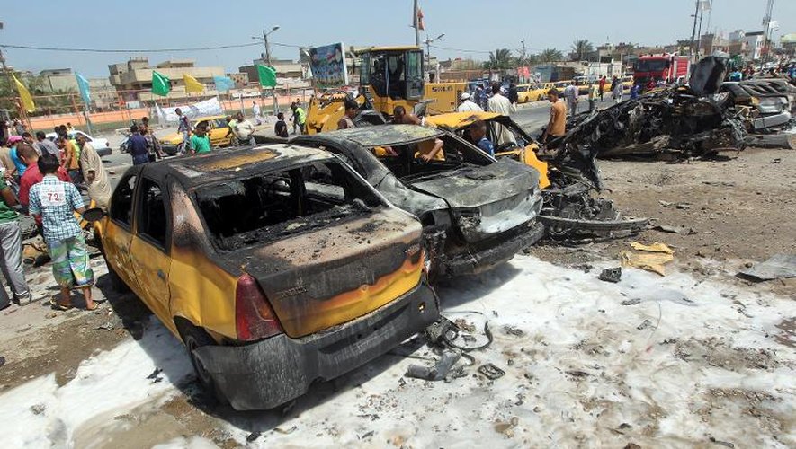 Des carcasses de voitures sur le site d'un attentat à la bombe dans un quartier chiite à Bagdad, le 13 mai 2014