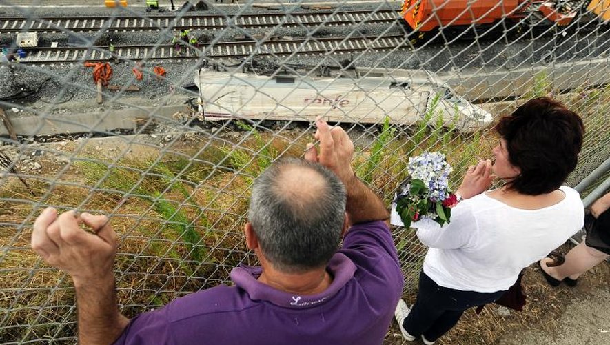 Deux personnes le 27 juillet 2013 à Angrois devant la locomotive du train qui a déraillé près de Saint-Jacques de Compostelle