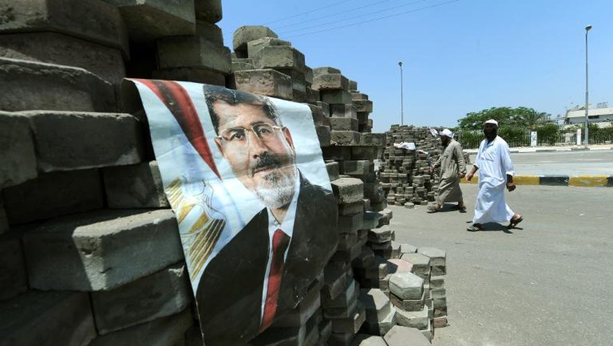 Des Egyptiens passent à côté d'un poster à l'effigie du président déchu Mohamed Morsi, le 28 juillet 2013 au Caire