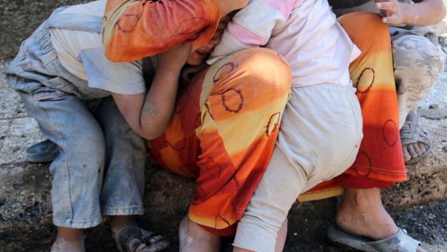 Une Syrienne rassure ses enfants après un bombardement à Alep, le 14 mai 2014