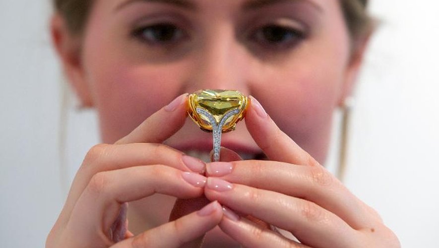 Une employée de Sotheby's exhibe le diamant jaune "Graff Vivid Yellow" de 100,09 carats, l'un de splus plurares de cette taille, à Londres le 11 avril 2014