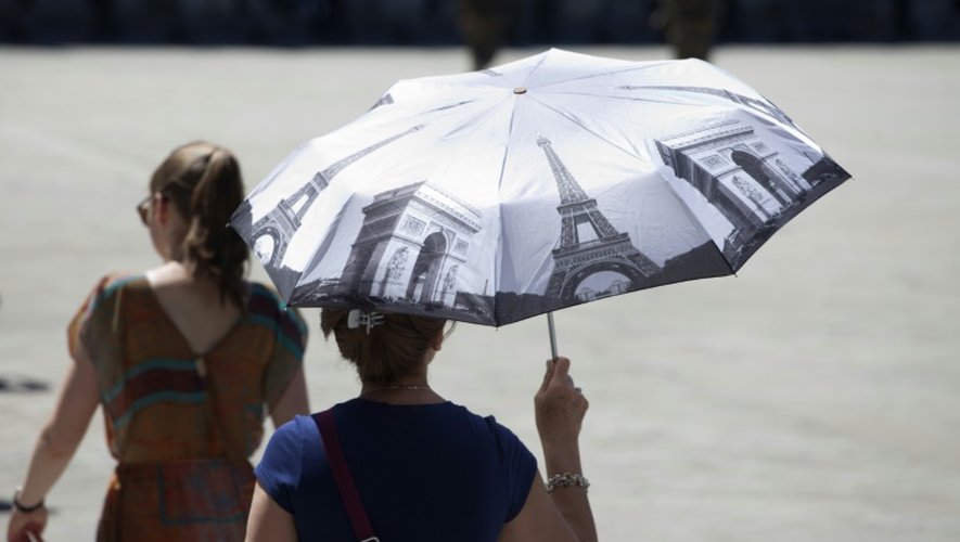 Une femme se protège du soleil sous un parapluie à Paris le 30 juin 2015