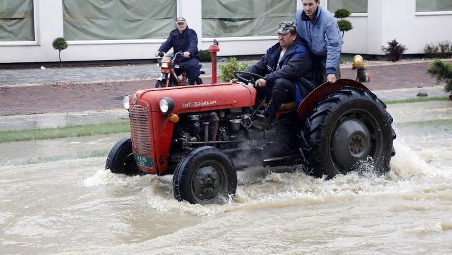 Des hommes utilisent un tracteur pour se déplacer après des inondations historiques à Banja Luka, en Bosnie, le 17 mai 2014