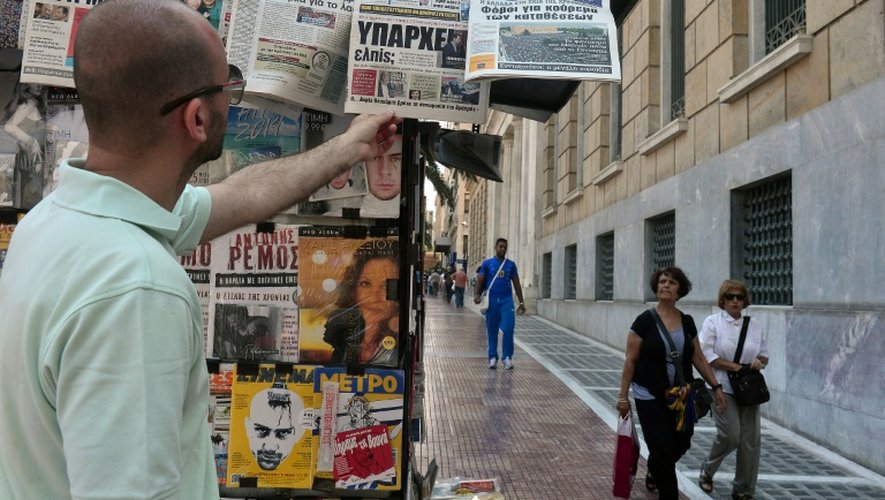 Un homme observe les Unes de journaux à Athènes, le 1er juillet 2015