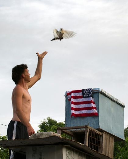 Un homme relâche un pigeon près d'un drapeau américain à La Havane le 1er juillet 2015, alors que Américains et Cubains ont annoncé la reprise des relations diplomatiques