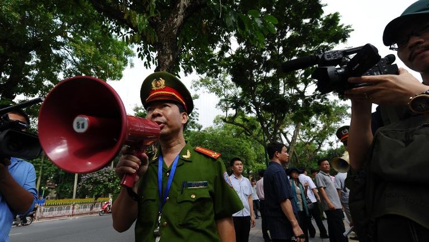 Des policiers demandent aux gens de quitter une rue proche de l'ambassade chinoise à Hanoi le 18 mai 2014