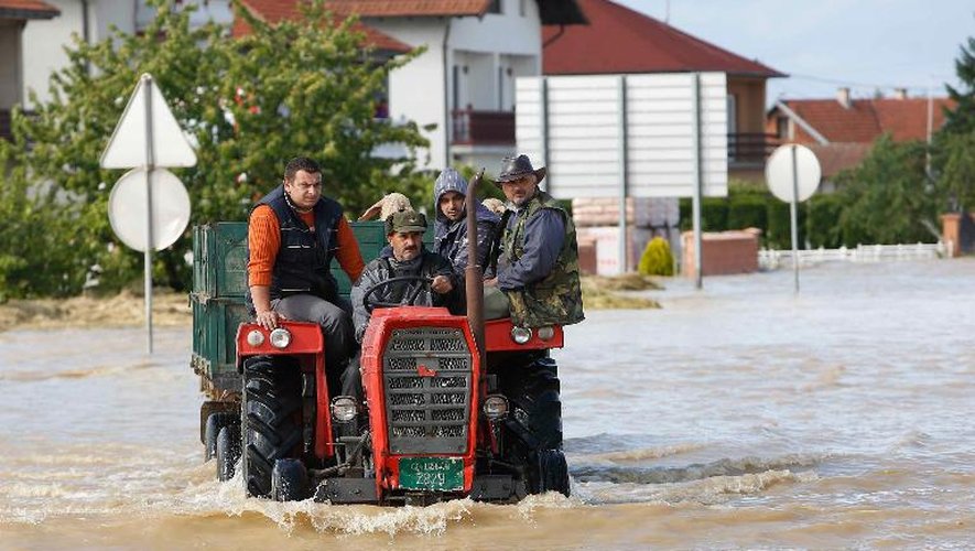 Des Bosniaques conduisent un tracteur dans une rue inondée de Bijeljina le 17 mai 2014
