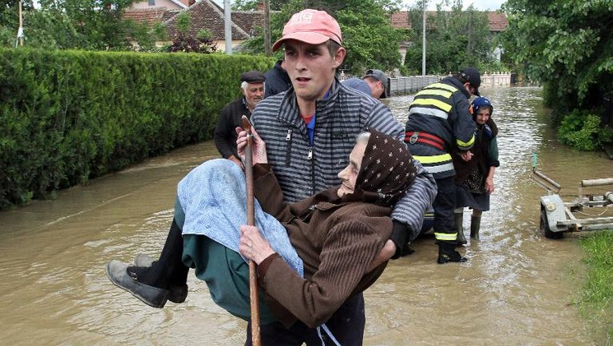 Un secouriste serbe porte une vieille femme hors de sa maison inondée dans le village d'Obrez le 17 mai 2014