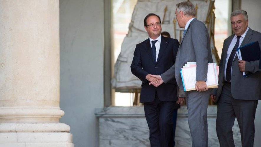 Le président François Hollande (g) et le Premier ministre Jean-Marc Ayrault (c) se serrent la main le 2 août 2013 après le dernier conseil des ministres avant les vacances d'été