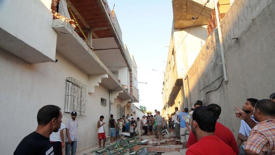 Des habitants se pressent autour des ruines d'une maison, détruite par un engin explosif, le 2 août 2013 à Jedeida près de Tunis