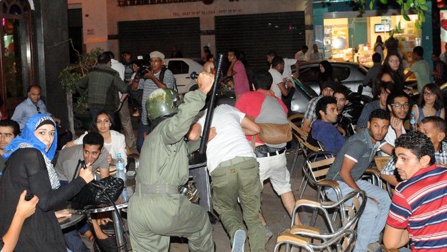 Un policier chasse des manifestants venus dénoncer la grâce accordée à un pédophile espagnol, le 2 août 2013 à Rabat