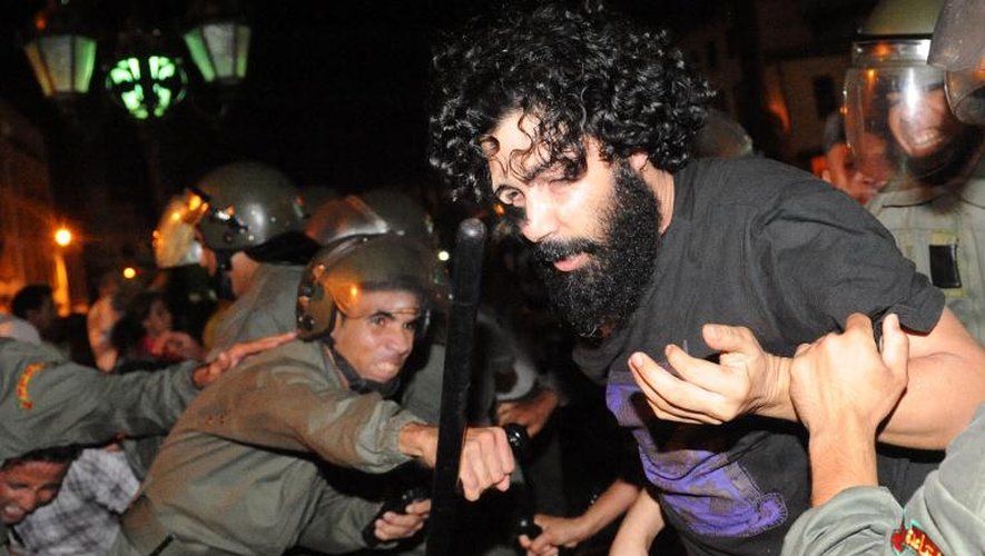 Un policier chasse un manifestant venu dénoncer la grâce accordée à un pédophile espagnol, le 2 août 2013 à Rabat