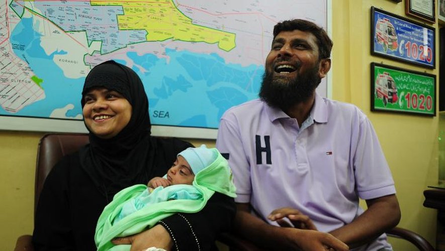 Riazuddin (d) et sa femme Tanzeem rient pendant que leur bébé adopté, Fatima, dort, le 1er août 2013 à Karachi