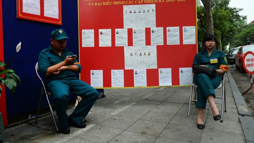 Deux policiers devant la biographies des candidats aux législatives dans un quartier de Hanoï, le 22 mai 2016