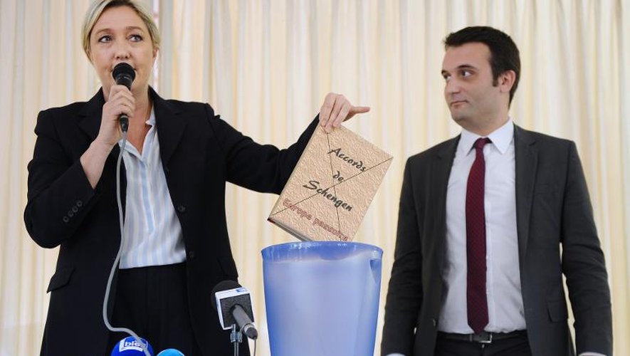 La dirigeante du Front national Marine Le Pen met symboliquement le texte des accords de Schengen sur la libre circulation à la poubelle, lors d'une réunion électorale le 16 mai 2014 à Apach dans l'est de la frnce