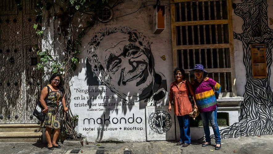 Des touristes posent devant une peinture murale représentant Gabriel GArcia Marquez à Carthagène le 22 mai 2016