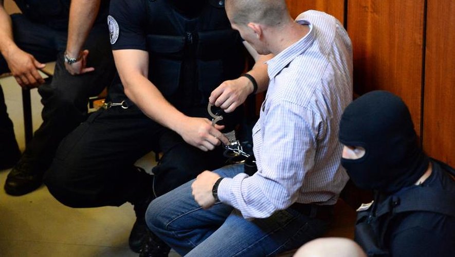 Un policier retire les menottes d'un homme accusé du meurtre de Roms, le 6 août 2013 dans un tribunal de Budapest