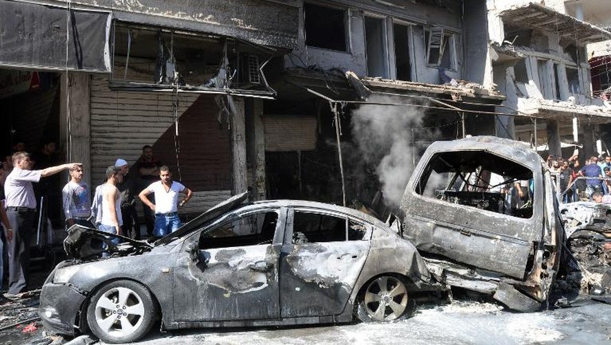 Des Syriens inspectent les lieux d'un attentat à la voiture piégée, le 25 juillet 2013 à Jaramana, dans la banlieue de Damas