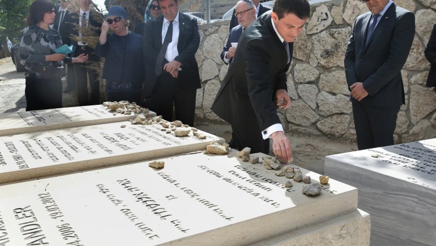 Manuel Valls (2e à d) dépose des cailloux sur les tombes de victimes françaises d'actes antisémites au grand cimetière Givat Shaul en Israël le 23 mai 2016