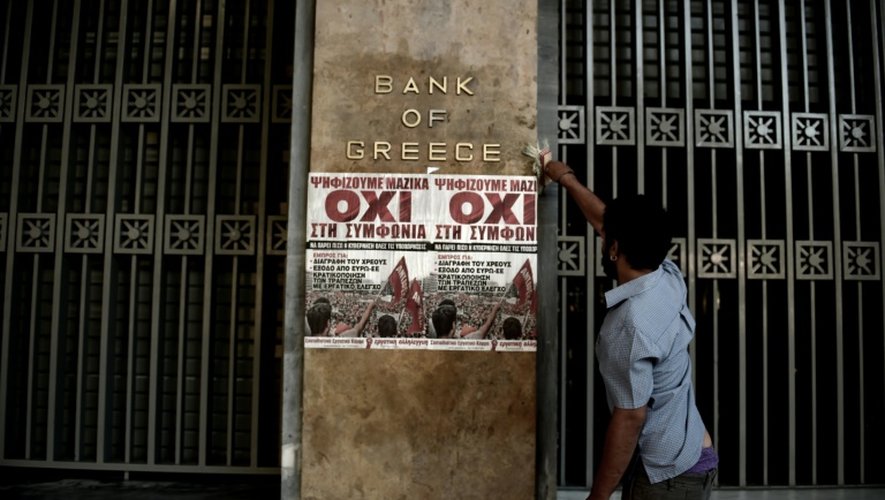 Un homme colle une affichette avec le slogan "No" sur la facade de la Banque de Grève, le 3 juillet 2015 à Athènes