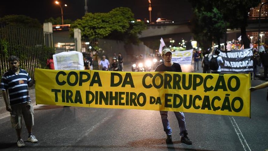 Défilé de protestataires qui brandissent une banderole avec les inscriptions "Coupe de la cooruption, vous gachez l'argent de l'éducation" contre la Coupe du monde de football 2014 au Brésil à Rio de Janeiro le 15 mai 2014