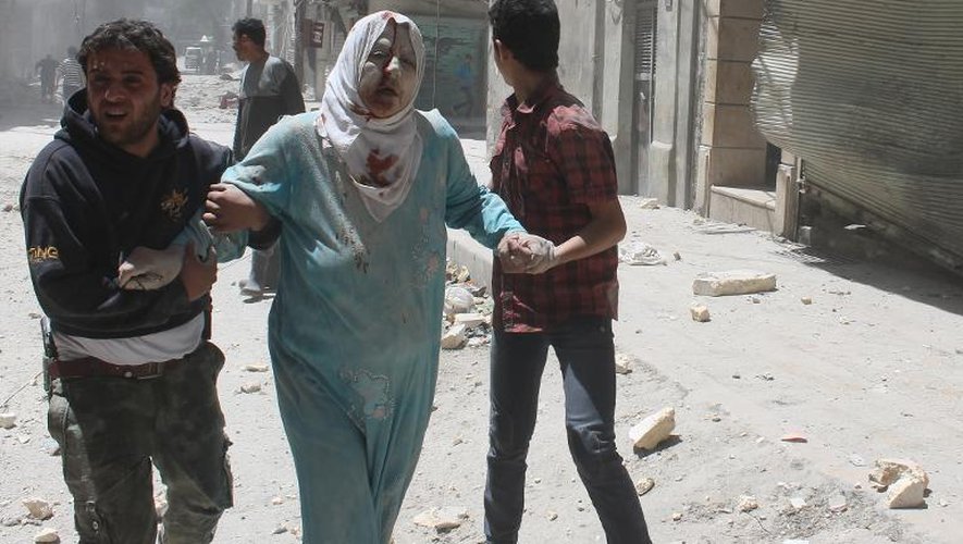 Syrian residents help an injured woman following reported air strikes by pro-regime forces in Aleppo's Al-Qatarji neighborhood, on May 18, 2014