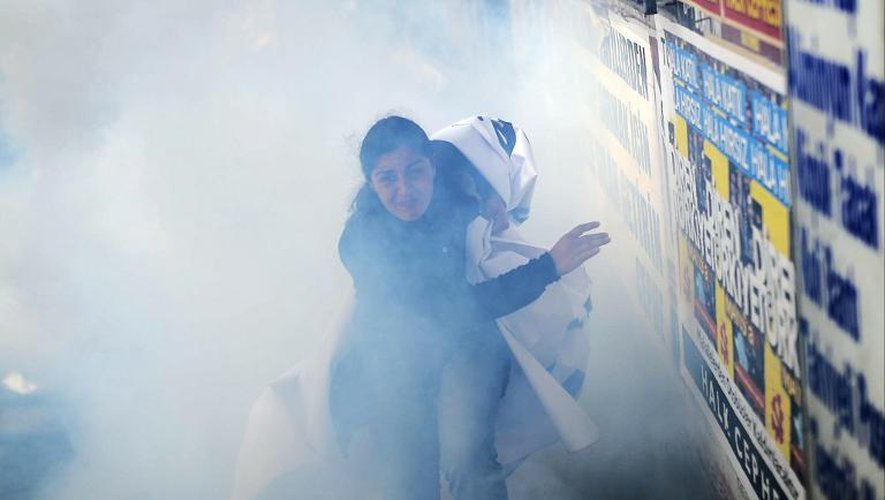 Une Turque fuit, dans les fumées des gaz lacrymogènes, les tirs de balles en caoutchouc et les canons à eau de la police anti-émeute pour disperser les manifestants, le 22 mai 2014, à Istanbul