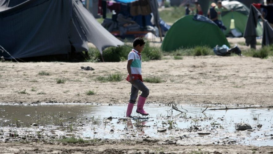 Un enfant marche dans la boue au milieu du camp de migrants d'Idomeni, à la frontière gréco-macédonienne le 23 mai 2016