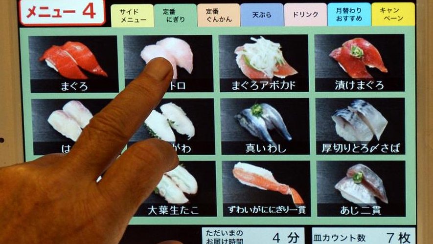 Un client fait son choix de sushi sur un écran tactile, le 18 juin 2013 à Tokyo
