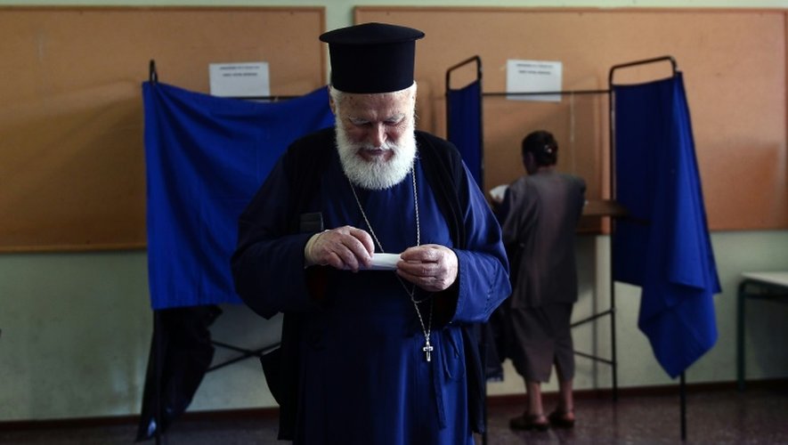 Un prêtre orthodoxe prépare son bulletin de vote à Athènes le 5 juillet 2015, jour du référendum national