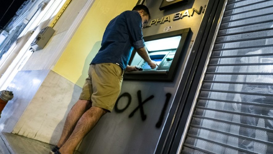 Un Grec retire de l'argent d'un distributeur bancaire à Athènes le 5 juillet 2015, jour du referendum en Grèce