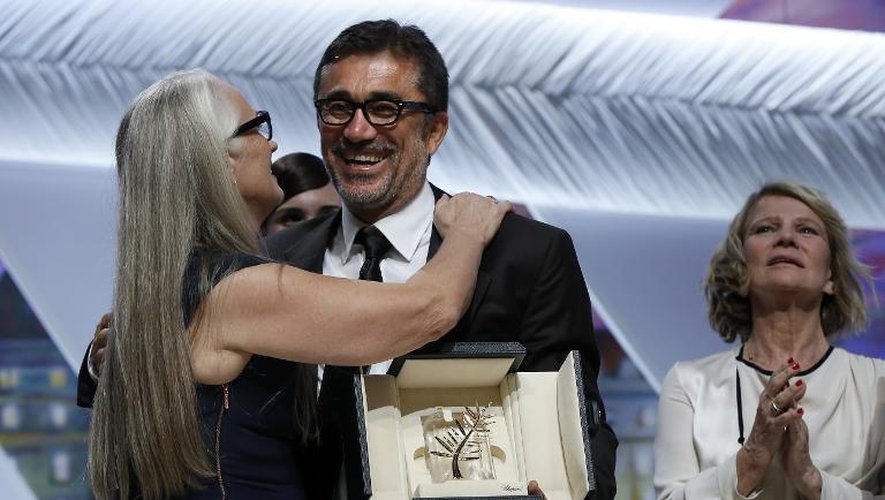 Le réalisateur turc Nuri Bilge Ceylan (c) félicité par la présidente du jury, Jane Campion, après avoir reçu la palme d'Or au 67e festival de Cannes le 24 mai 2014