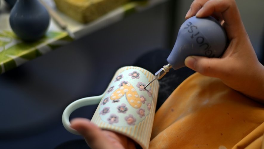 Un artisan décore une tasse dans l'atelier de poterie de Soufflenheim le 30 juin 2015