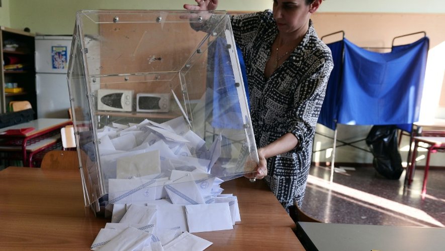 Une citoyenne grecque retourne une urne pour comptabiliser les votes du référendum à Athènes, le 5 juillet 2015