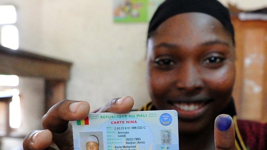 Une Malienne montre sa carte d'électrice et son doigt marqué à l'encre bleue, après avoir voté à Abidjan, le 11 août 2013