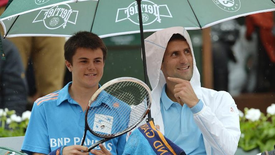 Le Serbe Novak Djokovic plaisante avec un ramasseur de balles lors d'une interruption en raison de la pluie, le 26 mai 2014 à Roland-Garros