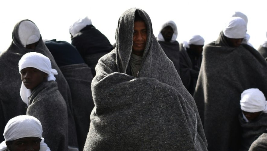 De smigrants se protègent du froid sous des couvertures à bord du navire de sauvetage "Aquarius" avant leur arrivée au port de Cagliari en Sardaigne le 26 mai 2016