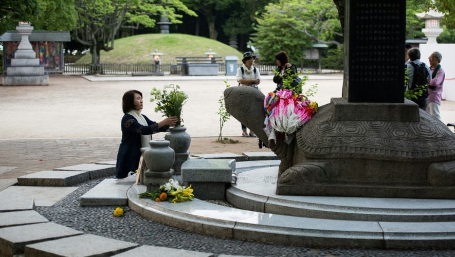 Une femme remplace des fleurs au Parc du mémorial de la paix à Hiroshima, le 26 mai