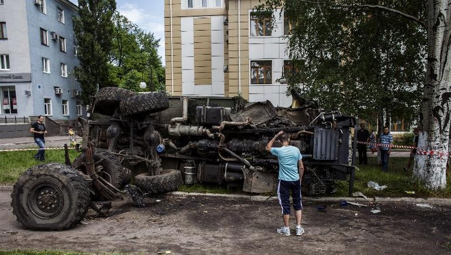 Un Ukrainien examine un véhicule utilisé par les rebelles prorusses et qui a été détruit le 27 mai 2014 par l'armée ukrainienne dans la ville de Donetsk, dans l'est du pays