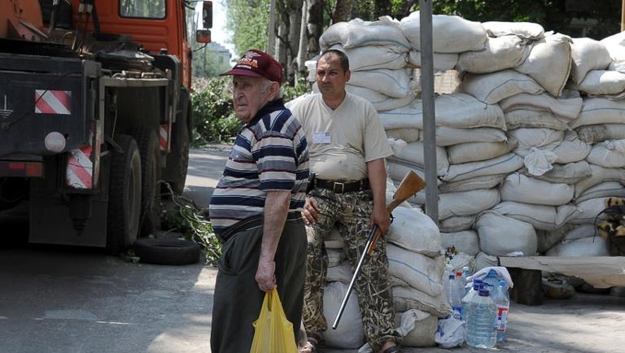 Un vieil homme se tient près d'un milicien prorusse armé gardant une barricade à Donetsk, dans l'est de l'Ukraine, le 28 mai 2014