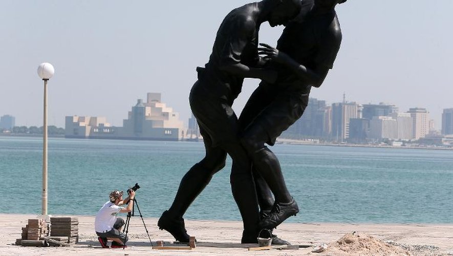 Un homme photographie la sculpture d'Adel Abdessemed immortalisant le coup de tête de Zidane sur Materazzi lors de la finale de la Coupe du monde 2006, le 4 octobre 2013 à Doha