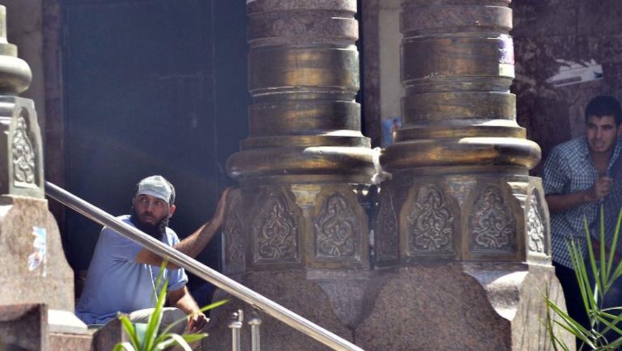 Des hommes se protègent derrière des colonnes tandis que la police tire en direction de pro-Morsi, retranchés dans une mosquée, le 17 août 2013 au Caire