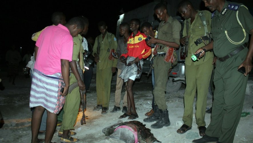 Des soldats somaliens se tiennent près du corps d'un des assaillants présumés d'un hôtel à Mogadiscio, le 10 juillet 2015