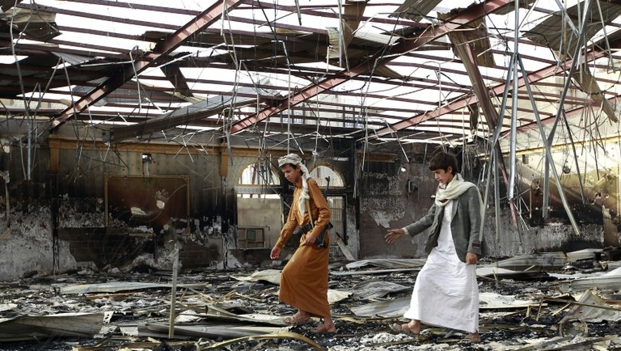 Des Yéménites marchent au milieu des décombres d'un bâtiment touché par une frappe de la coalition dirigée par l'Arabie saoudite, le 10 juillet 2015 à Sanaa