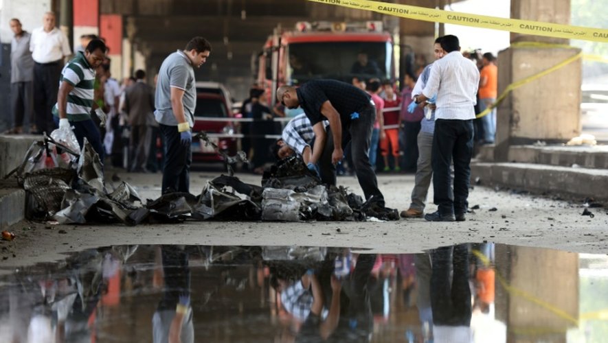 Des experts autour de la voiture piégée utilisée dans un attentat contre le consulat italien le 11 juillet 2015 au Caire