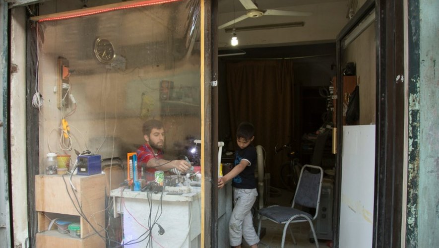 Un Syrien travaille dans son magasin dont la fenêtre a été remplacée par du plastique à Alep le 24 mai 2016