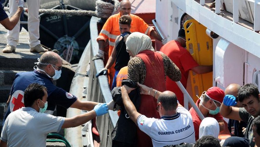 Des garde-côtes aident des immigrés clandestins à débarquer, le 19 août 2013 au port de Catane, en Sicile