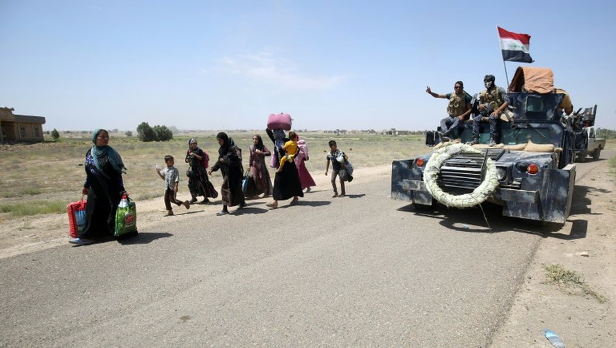 Des familles qui quittent Fallouja croisent des soldats de l'armée irakienne en route pour la ville située à 50 km à l'ouest de Bagdad, le 27 mai 2016