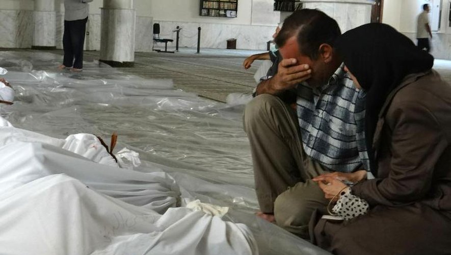 Photo fournie par le réseau d'opposition syrienne Shaam News montrant un couple pleurant face aux cadavres de proches, tués lors d'une attaque qui pourrait être d'origine chimique, le 21 août 2013 près de Damas