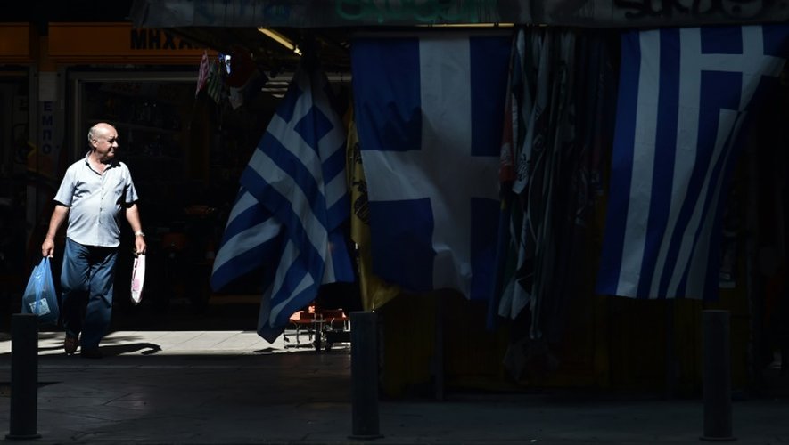 Un homme passe devant des drapeaux grecs déployés sur une échoppe du centre d'Athènes, le 13 juillet 2015